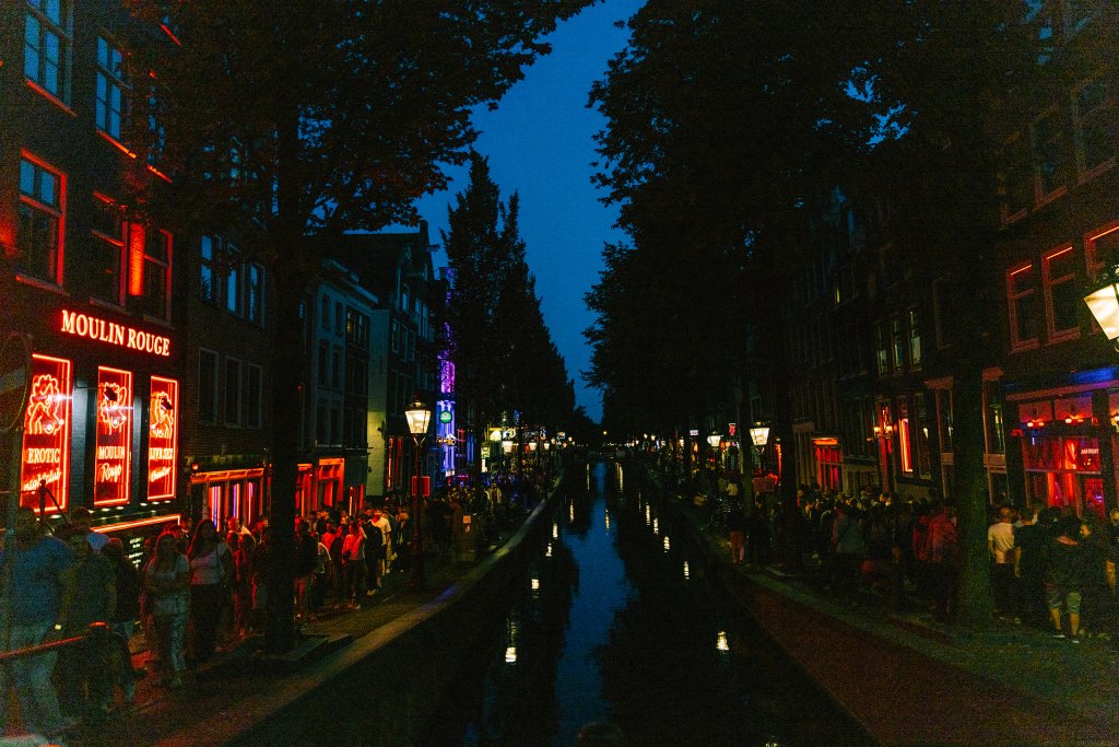 Blick auf Kanal in Amsterdamer Rotlichtviertel. Abendstimmung mit leuchtenden Reklamen.