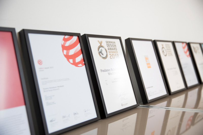 Eine Reihe gerahmter Auszeichnungen, darunter Red Dot und German Design Award.